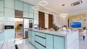 A modern kitchen with a central island, built-in appliances, and a large TV.