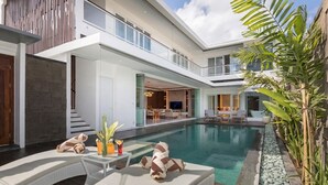 A modern pool area with lounge chairs and a dining area.