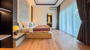 A modern hotel room with a large bed, a desk, a lamp, and a view of the outdoors.