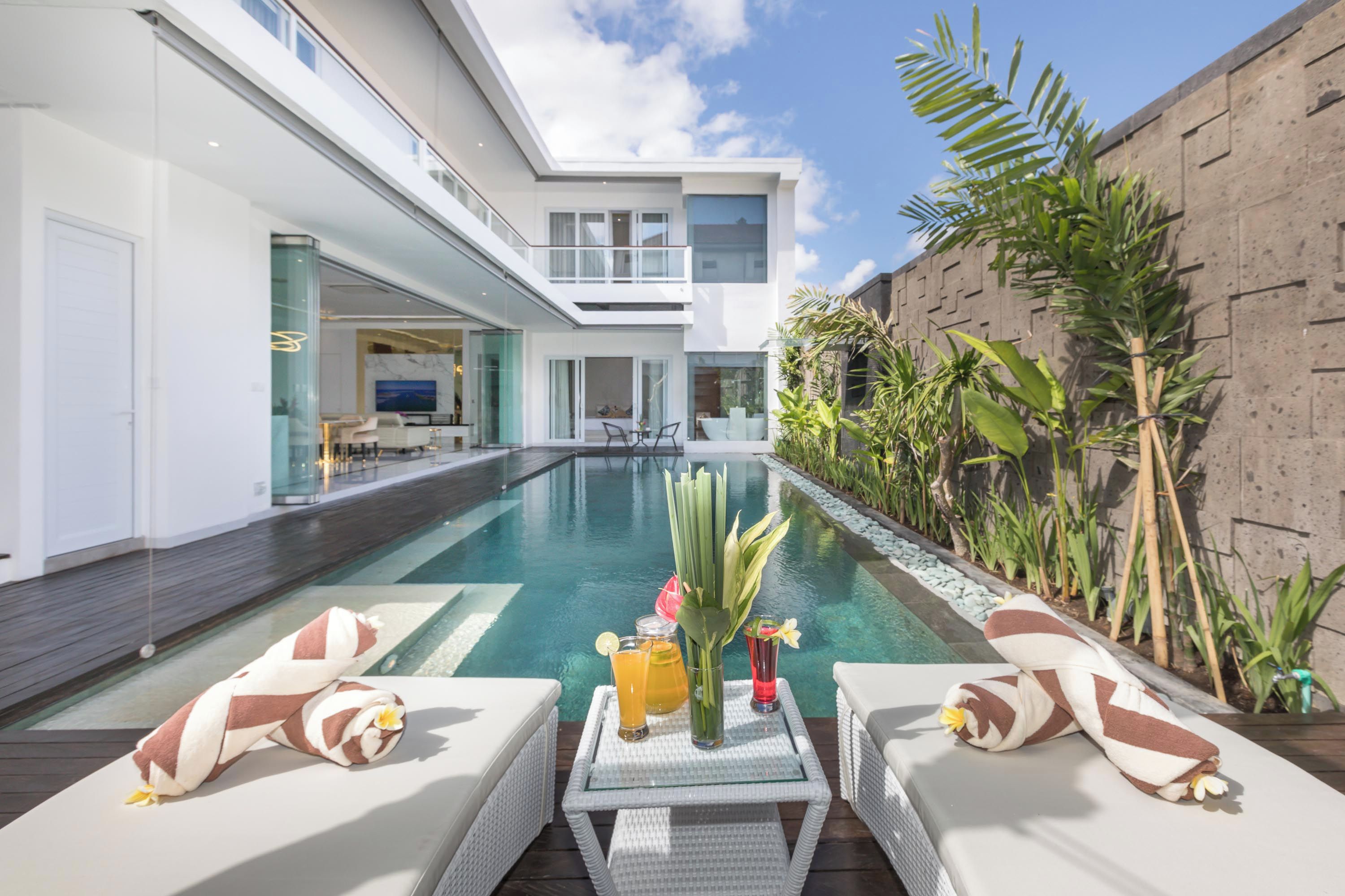 A modern poolside area with lounge chairs, a table with drinks, and a view of the pool.