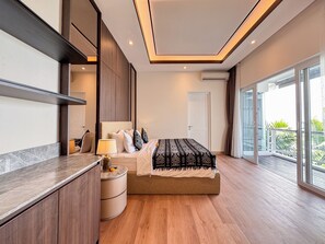Une chambre d’hôtel moderne avec un grand lit, une table de chevet, une lampe et une vue sur l’extérieur.