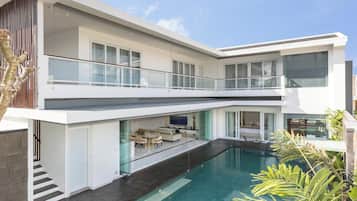 A modern two-story house with a swimming pool, a balcony, and a dining area.