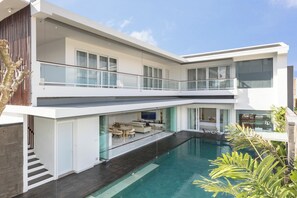 Ein modernes, zweistöckiges Haus mit Schwimmbad, Balkon und Essbereich.