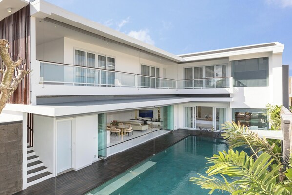 A modern two-story house with a swimming pool, a balcony, and a dining area.