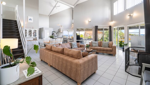 A spacious living area with a staircase, a kitchen, and a dining area.