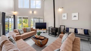 A spacious living room with a large TV, a fireplace, and a balcony with a view.