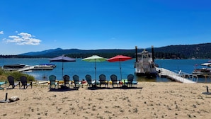 Un entorno junto al lago con un muelle, sillas y sombrillas.