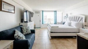 Une chambre moderne avec un lit, un canapé, une télévision et une fenêtre avec des rideaux.
