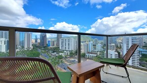 Un balcón con vistas a un paisaje urbano, incluyendo rascacielos y palmeras.