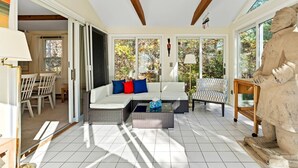 A sunlit room with a white sofa, a patterned armchair, and a stone sculpture. - Bike trail, Tennis Court, Surrounded by nature (Eastham)