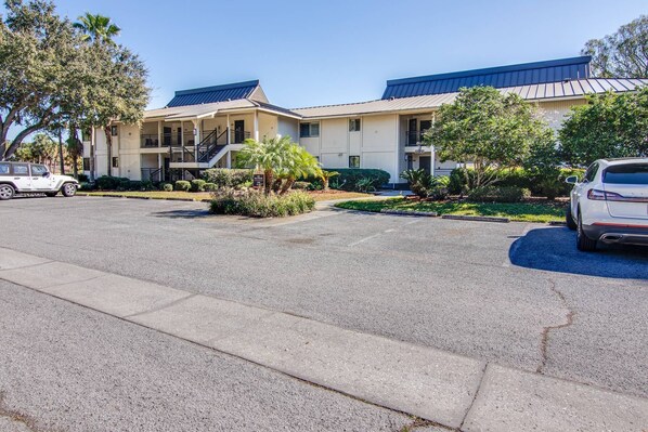 A two-story building with a covered parking area and a landscaped garden.