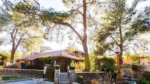 A house with a stone facade, a tiled roof, and a front yard with a small pool and a gas pump. - Stylish & Comfy ~ 5★ Location, Office, ♛Queen Bed (Ridgecrest)