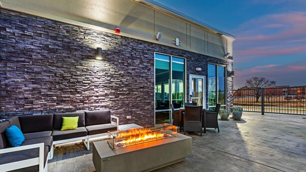 An outdoor patio with a stone wall, a fire feature, and seating. - Hampton Inn & Suites Canyon (Canyon)