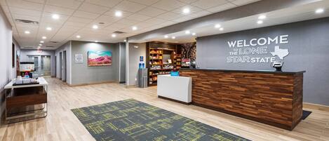 A reception area with a reception desk, a welcome sign, a display of local products, and a seating area with a patterned rug.