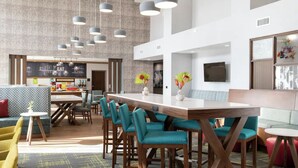 A modern hotel lobby with a bar area, seating arrangements, and a large wall with artwork. - Hampton Inn & Suites Canyon (Canyon)