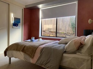 Una camera da letto con un letto, una finestra vista giardino e un quadro appeso al muro.