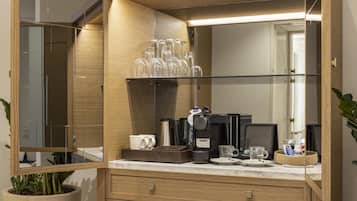 A modern bathroom with a wooden vanity, a glass shower enclosure, and a coffee maker on the counter.