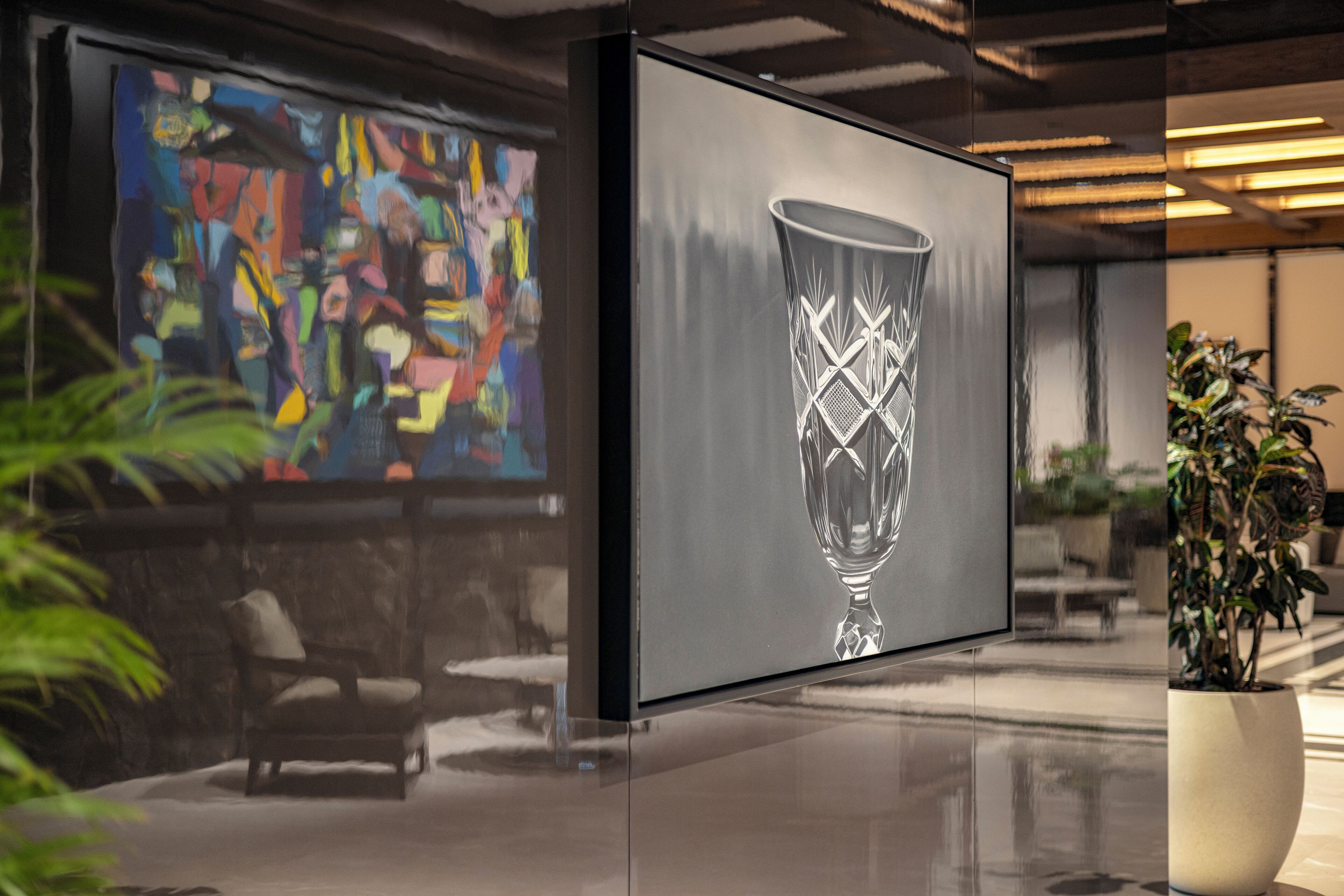 Un intérieur moderne agrémenté d’un grand tableau abstrait, d’une sculpture en verre et d’une plante en pot.