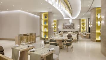 A modern dining area with round tables, chairs, and a central light fixture.