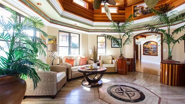 A spacious lobby with wicker furniture, a central round table, and large potted plants. - Serene Business-Friendly Getaway ~ ♛Queen Bed, Pkg (Ridgecrest)