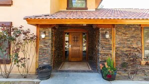 A house with a stone facade, a tiled roof, and a wooden front door. - Serene Business-Friendly Getaway ~ ♛Queen Bed, Pkg (Ridgecrest)