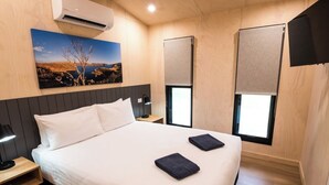 A hotel room with a bed, bedside tables, a painting, and windows with blinds. - Discovery Resorts- Lake Argyle (Lake Argyle)