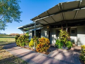 A modern building with a covered patio area, surrounded by landscaped gardens and a clear blue sky. - Discovery Resorts - Lake Argyle (Lake Argyle)