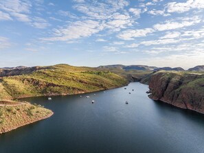 A river with boats, surrounded by green hills and a clear sky. - Discovery Resorts - Lake Argyle (Lake Argyle)