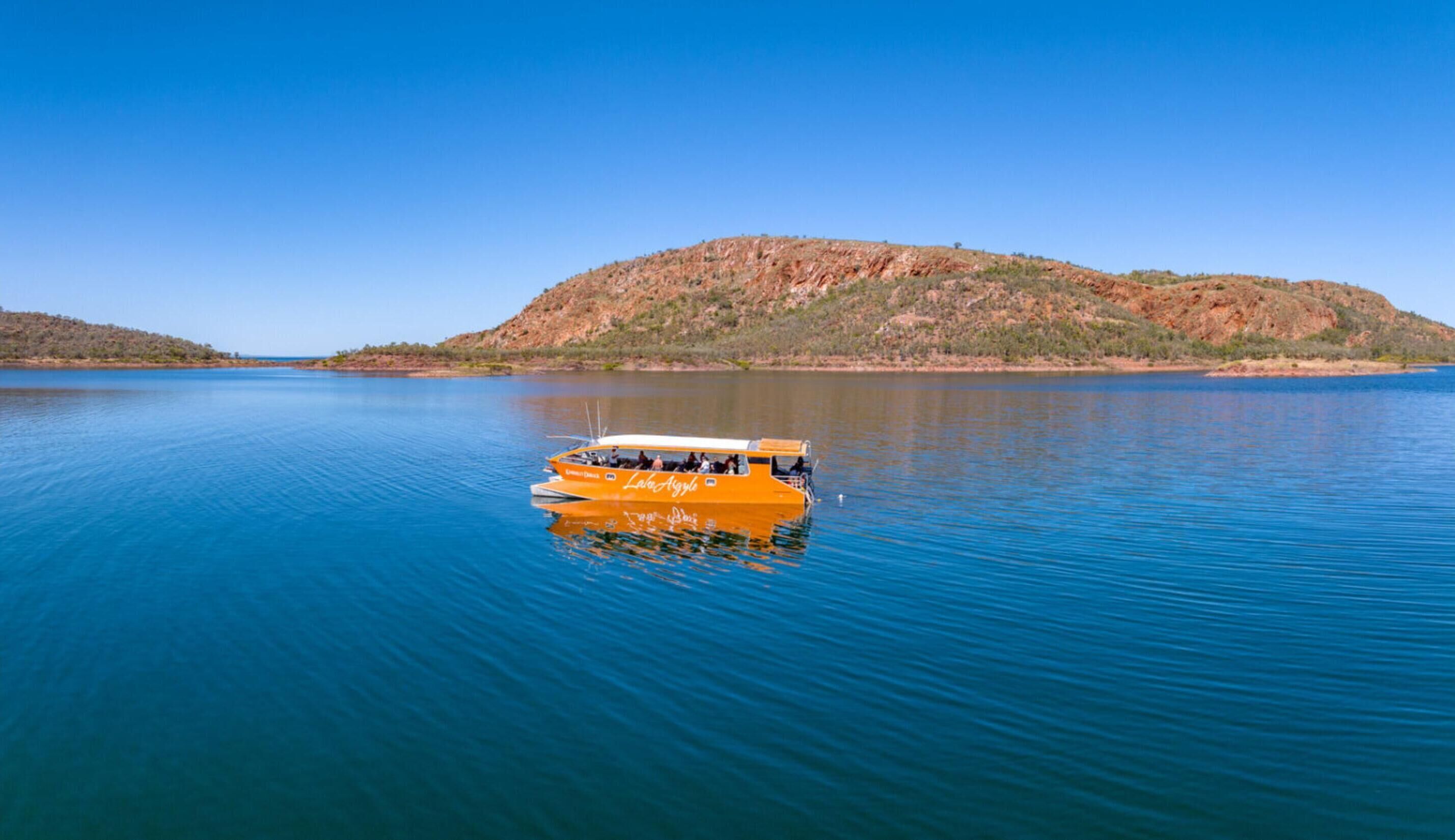Un bote sobre aguas tranquilas con un paisaje montañoso al fondo.