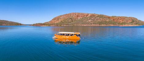Un bote sobre aguas tranquilas con un paisaje montañoso al fondo.