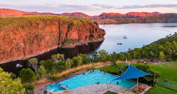 A swimming pool with a view of red rock formations and a lake. - Discovery Resorts - Lake Argyle (Lake Argyle)