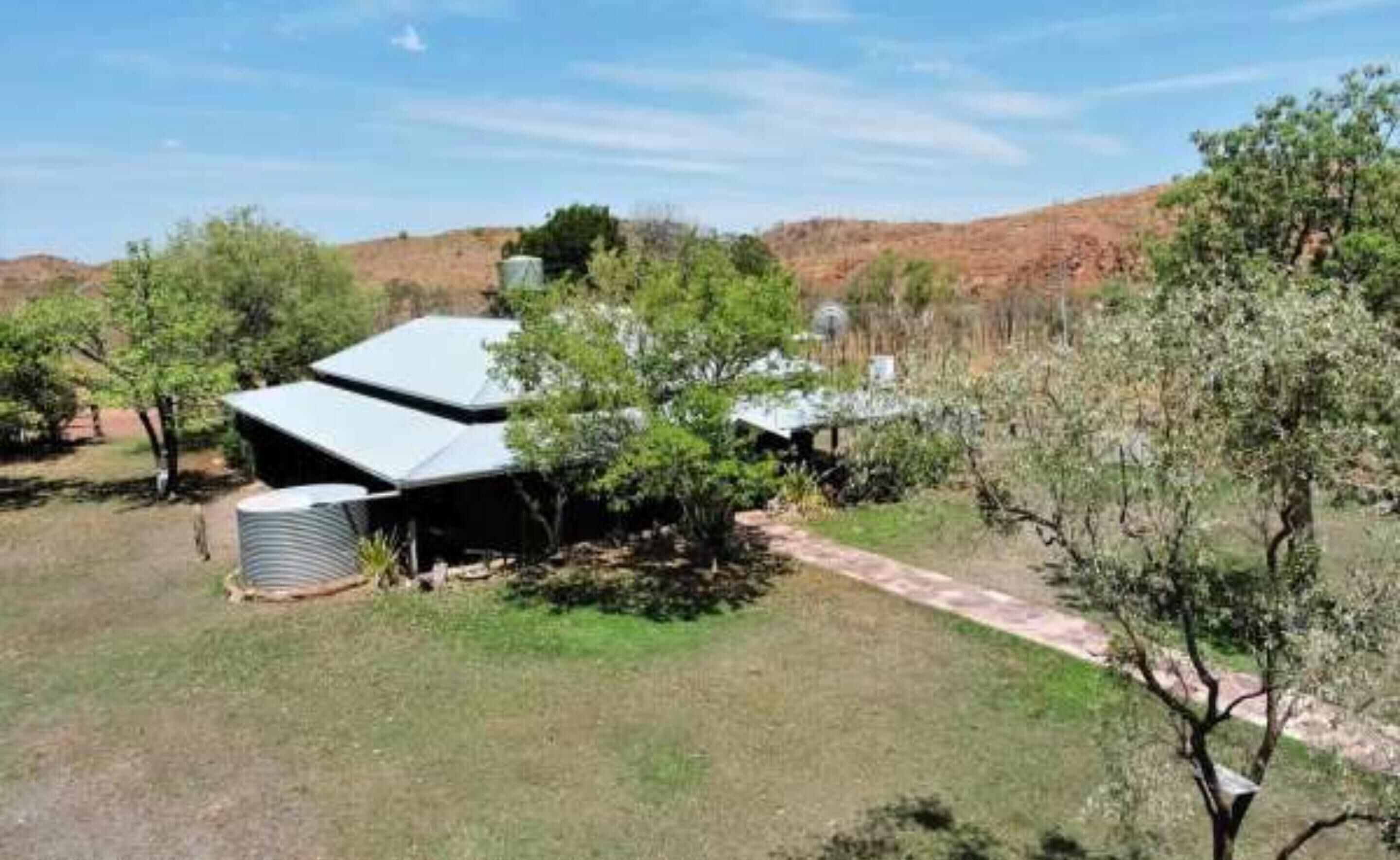 Una casa con techo inclinado, rodeada de árboles y un paisaje montañoso.