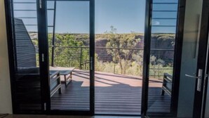 A room with a sliding glass door leading to an outdoor deck with a bench.