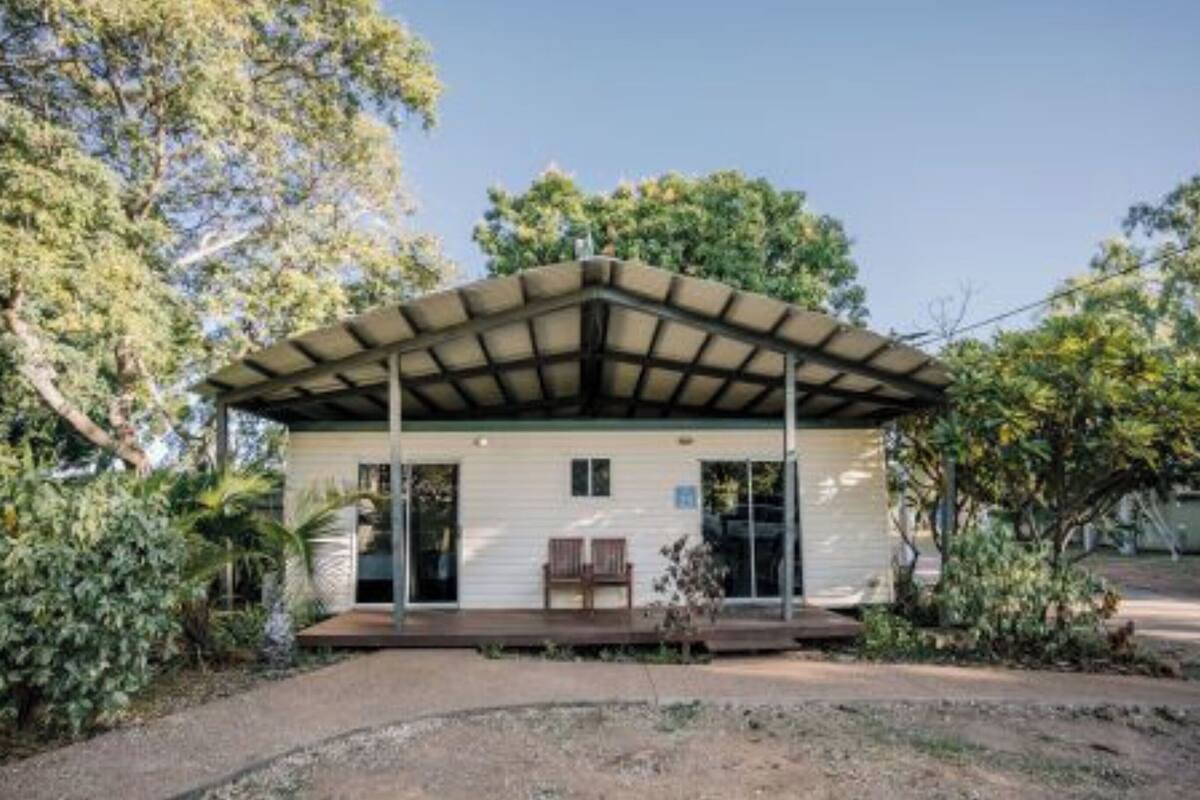 Ein eingeschossiges Haus mit einer Veranda, umgeben von üppigem Grün.
