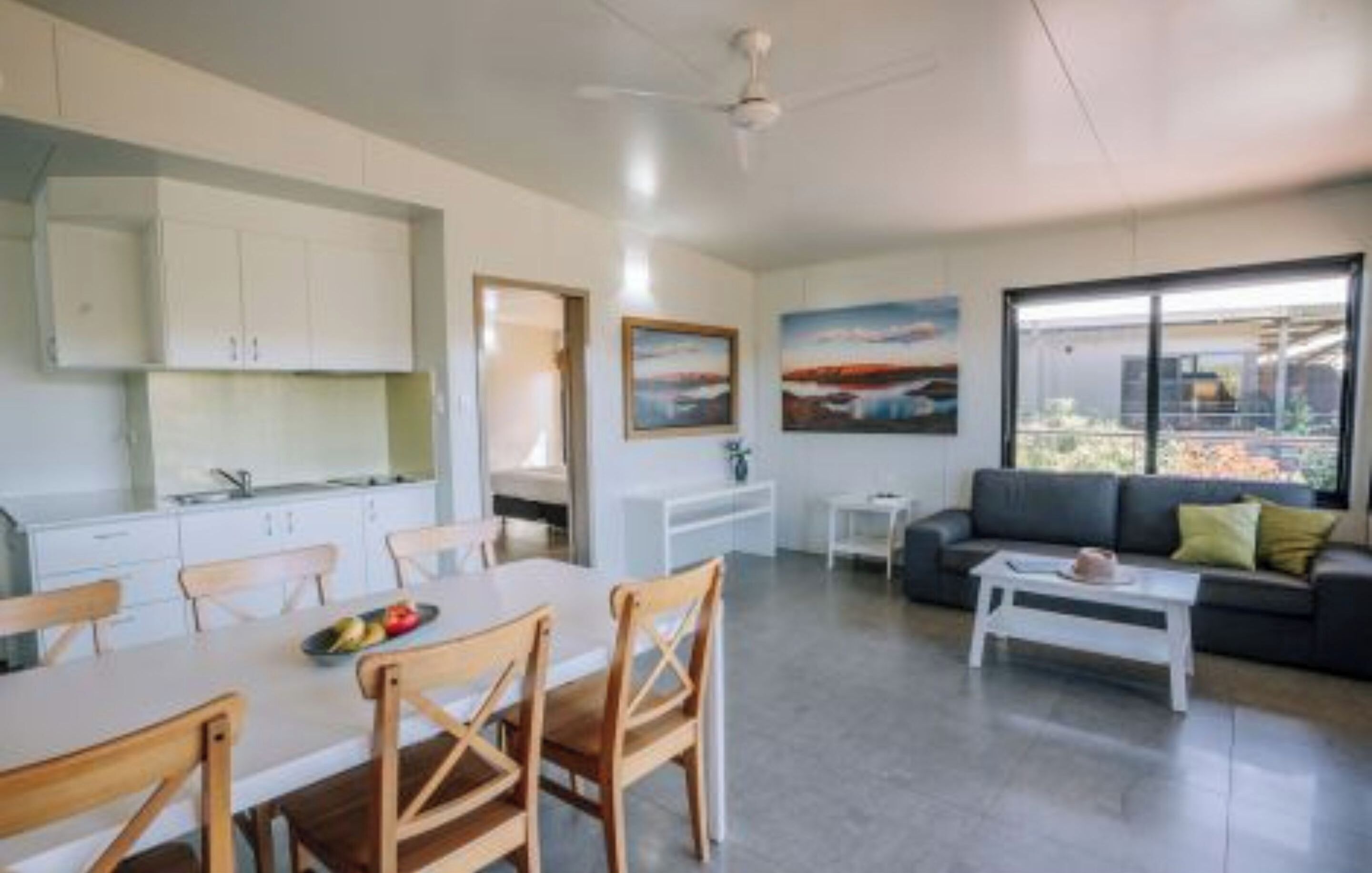 A modern living space with a dining area, kitchen, and a sofa with a view.