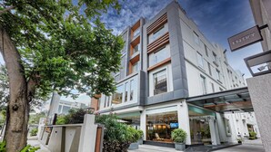 A modern building with a glass entrance, a sign indicating an entry point, and a staircase leading to the entrance. - The Sulit Whitefield (Bengaluru)