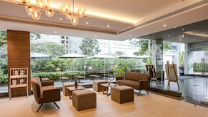 A modern indoor space with seating, tables, and a large window overlooking greenery. - The Sulit Whitefield (Bengaluru)