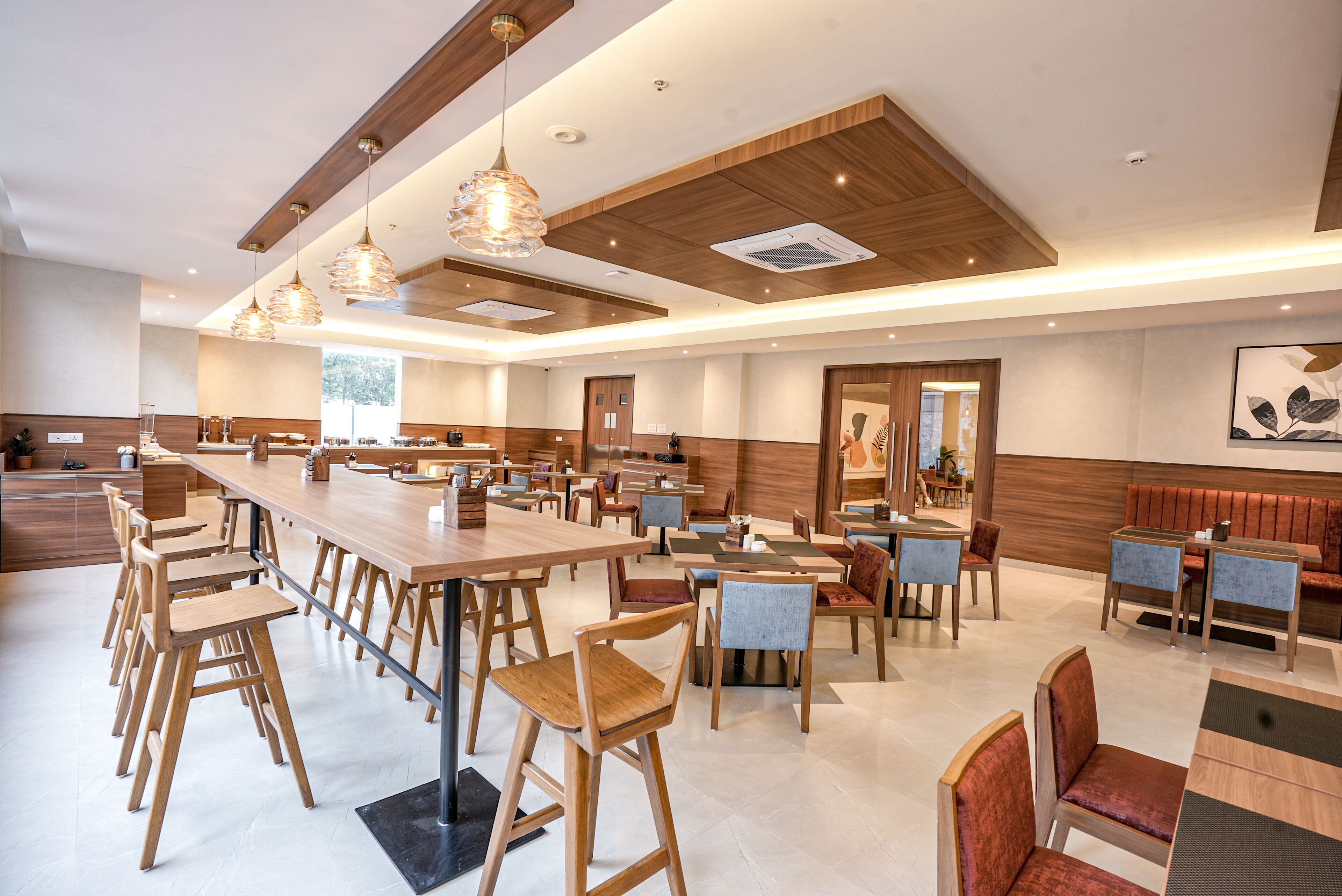 A spacious dining area with multiple tables and chairs, wooden accents, and pendant lighting.