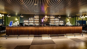 A modern bar area with a neon sign, a variety of bottles, and a check-in counter. - The Sulit Whitefield (Bengaluru)