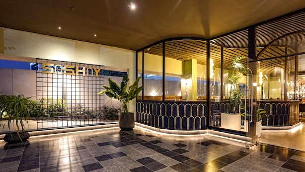 A modern hotel lobby with a checkered floor, a reception desk, and potted plants. - The Sulit Whitefield (Bengaluru)