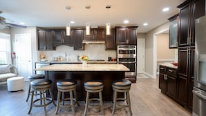 A modern kitchen with dark wood cabinets, stainless steel appliances, and a central island with bar stools.