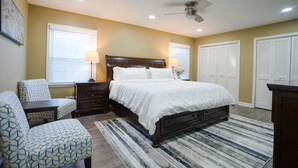 A bedroom with a bed, two nightstands, a chair, a dresser, and a ceiling fan.
