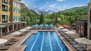 A swimming pool with lounge chairs and umbrellas, surrounded by buildings and a mountainous landscape. - Westin Riverfront - Beaver Creek - 1 bedroom (Avon)