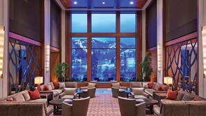A lobby with a large window offering a mountain view, multiple seating areas with sofas and armchairs, and decorative wall panels. - Westin Riverfront - Beaver Creek - 1 bedroom (Avon)