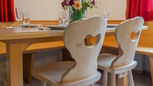 A dining table with two chairs, a vase with flowers, and a glass of water on the table. - Spacious holiday home, ideal for families with children. (Brixen im Thale)