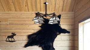 A wooden dining table with chairs, a moose wall decal, and a chandelier. - Beautiful hand-crafted log cabin on Horse Creek one block off Main Street. (Dubois)