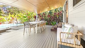 Eine Terrass mit Holzdeck, einem Tisch mit Stühlen und einer gepolsterten Sitzecke.