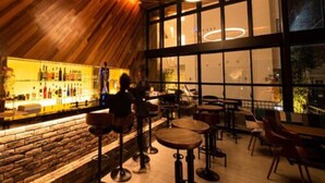 A bar area with wooden ceiling, circular light fixtures, and a bar counter with bottles. - Hotel Brick (Naha)