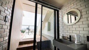 A modern bathroom with a large mirror, a sink, and a view of a balcony. - Hotel Brick (Naha)