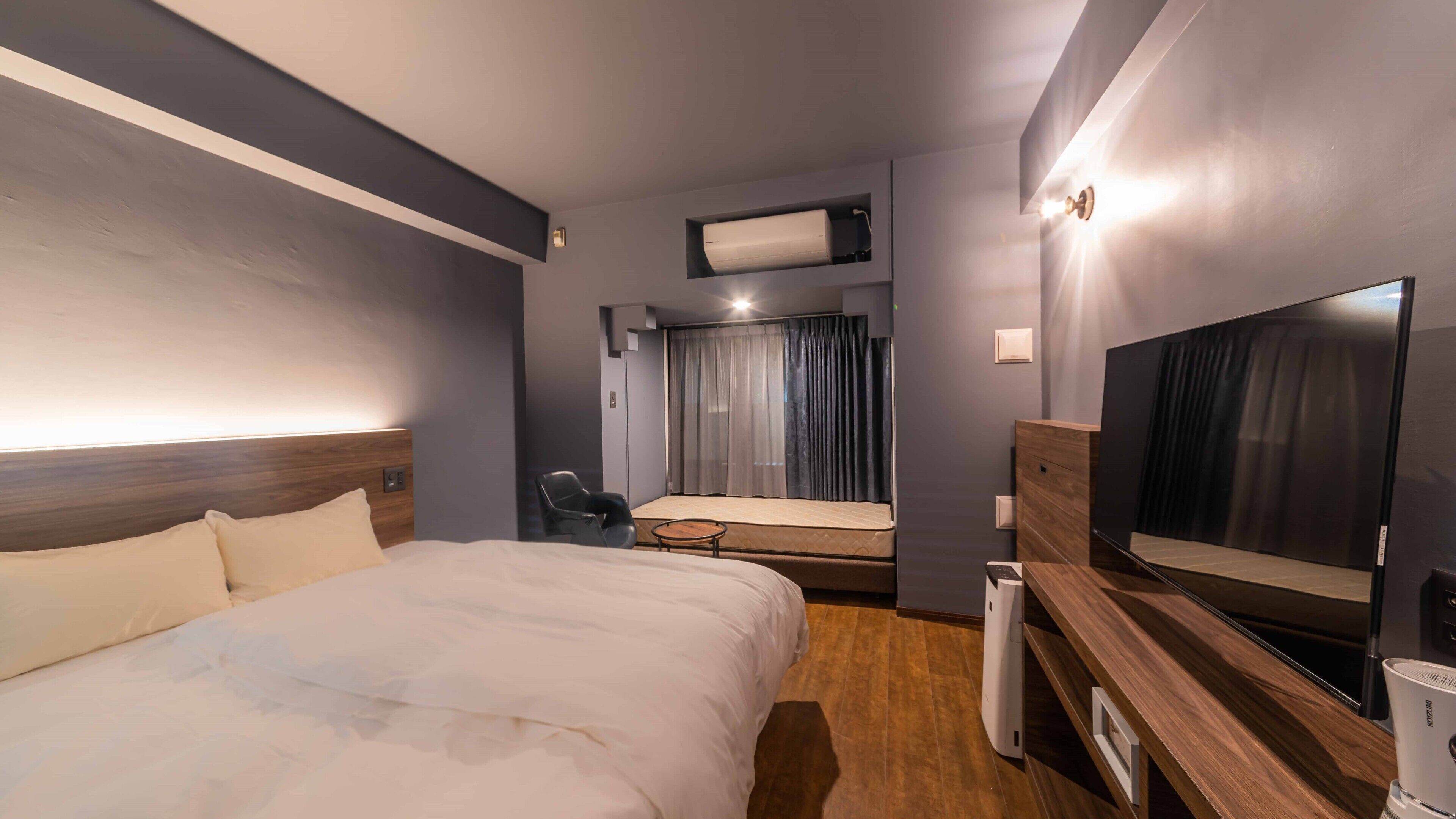 A hotel room with a bed, a desk, a chair, a television, and a window with curtains.